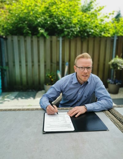 Felix Fuchs unterschreibt Dokumente auf der Terrasse