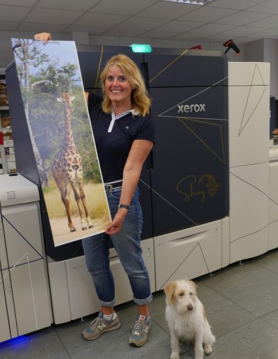 Birgit Hermes mit Poster im Bannerformat mit Giraffenmotiv und ihrem Hund Jessie